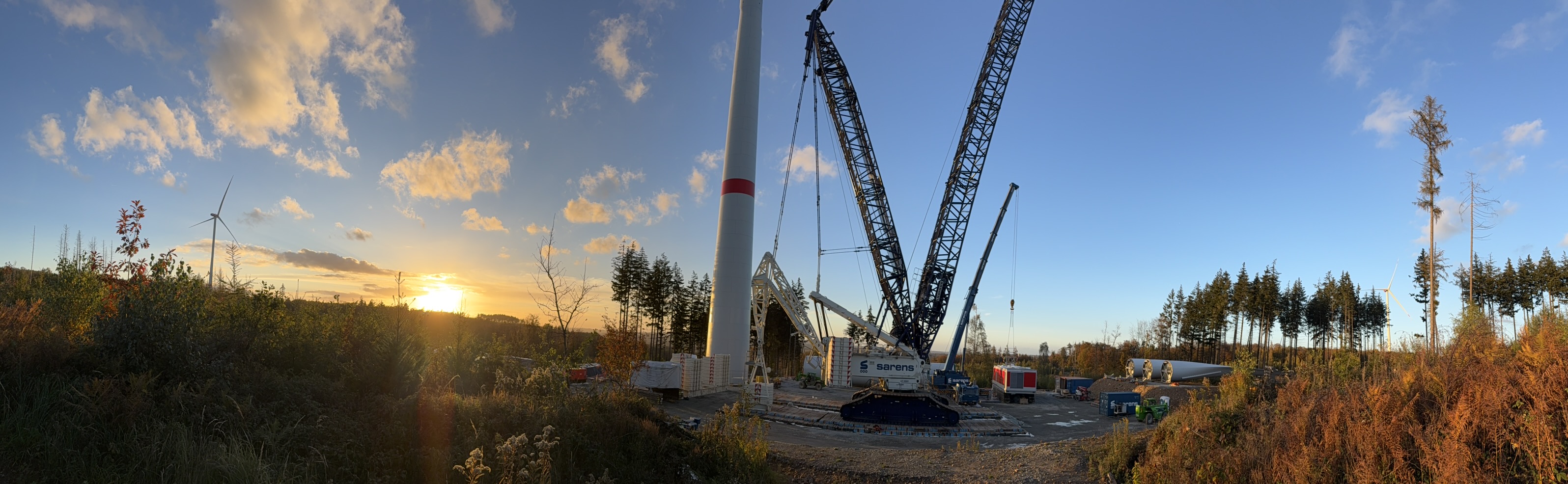 Abendsonne über der Haiderbach mit Windradturm, Baukränen, offenen Flächen und verbliebenen Bäumen