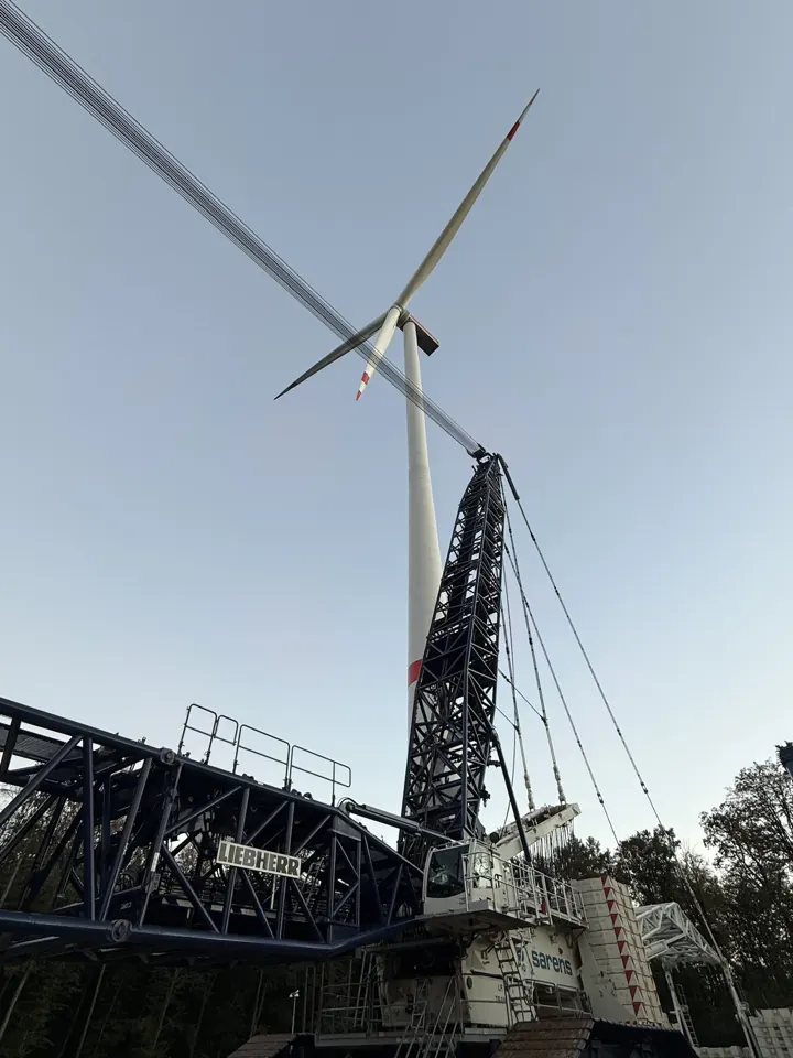 Windrad und Kräne von unten im Abendlicht
